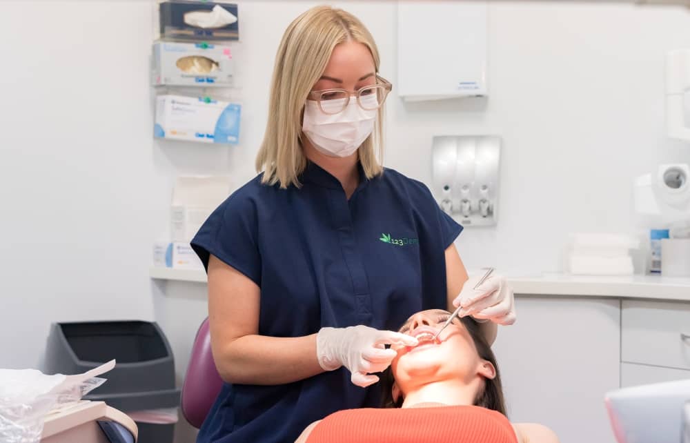 Young woman undergoing dental procedure, 123 Dental.