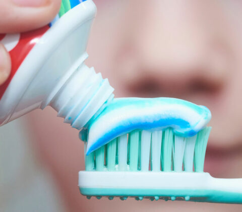 adding toothpaste to toothbrush