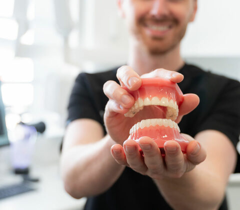dentist holding teeth model with invisalign