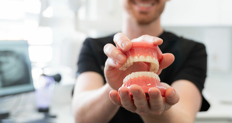 dentist holding teeth model with invisalign