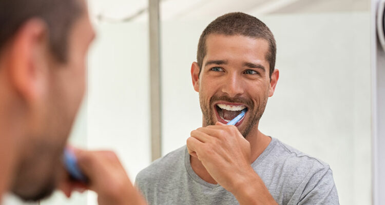 man with veneers brushing teeth in mirror