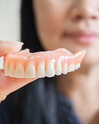 woman holding dentures in hand