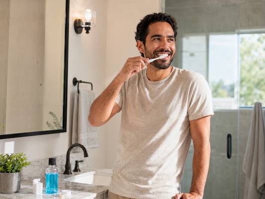 man brushing teeth while smiling